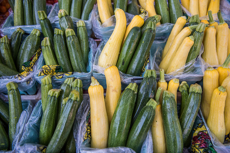farmers market containers with green zucchini and yellow squash