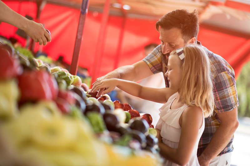 Father and daughter looking at produce at a farmers' market