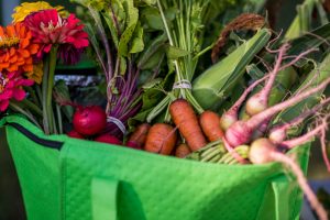 green fabric bag with carrots radish and flowers