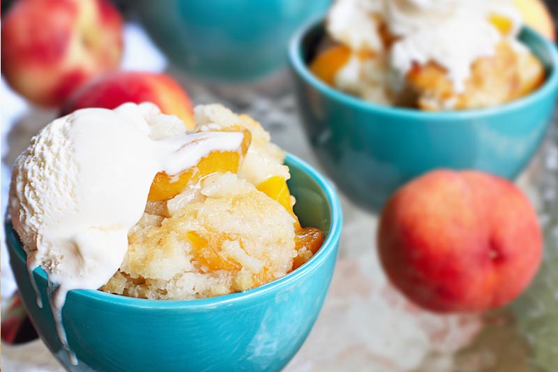 Peach cobbler in teal bowls with ice cream